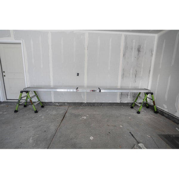 Eine lange Arbeitsplattform aus Aluminium auf zwei stabilen Leitern in einer Garage zur Renovierung.
