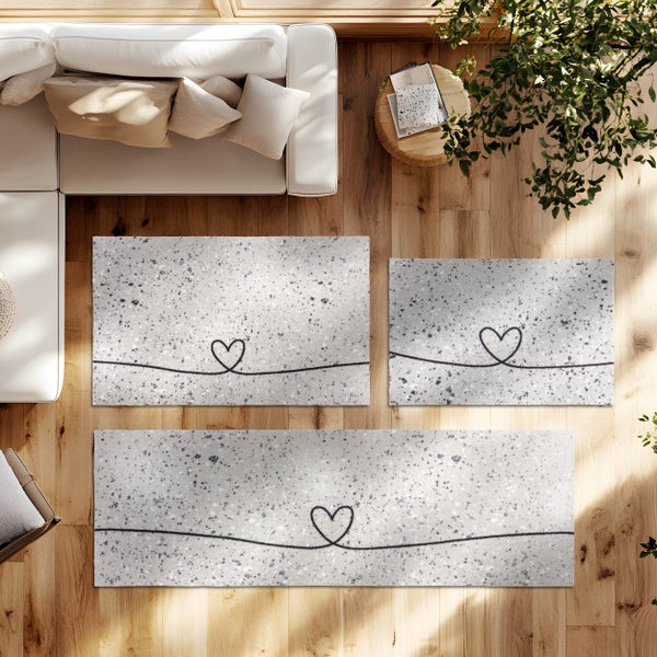 Teppiche und Läufer mit Herz-Design in einem hellen Wohnzimmer auf Holzboden neben einem weißen Sofa.