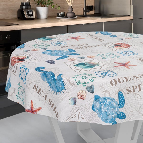 Runde Tischdecke mit maritimem Motiv aus Schildkröten, Seepferdchen, Seesternen und Schriftzügen auf hellem Untergrund mit Holzstruktur.