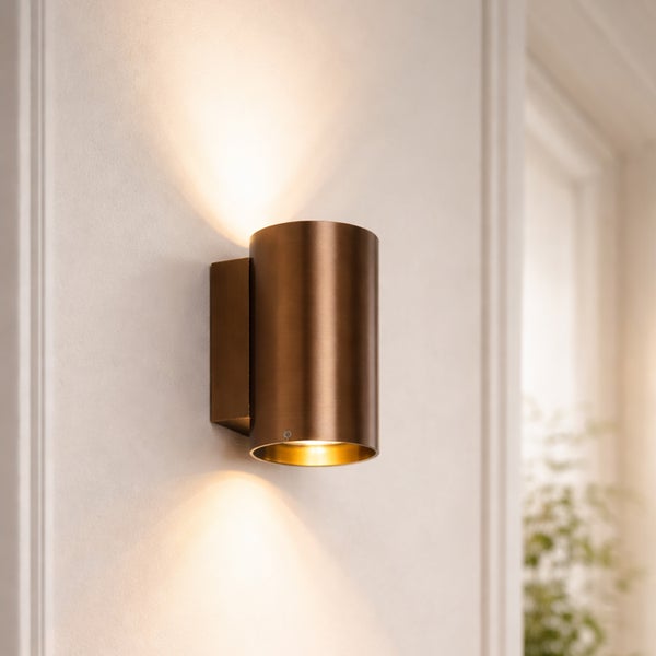 Moderne zylindrische Wandleuchte für den Innenbereich mit direktem und indirektem Lichtkegel an einer Wand montiert