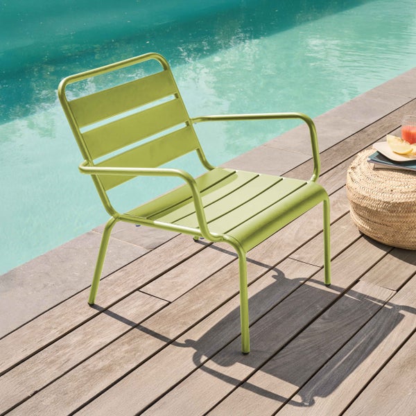 Grüner Garten-Loungesessel aus Metall mit Lamellen auf einer Holzterrasse am Pool.