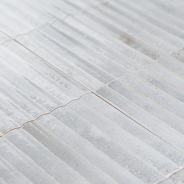 Wandfliesen mit strukturierter Oberfläche und wellenförmigen Kanten verlegt im Verband.