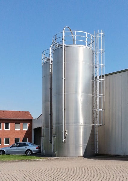 Zwei Edelstahltanks mit Leiter vor blauem Himmel