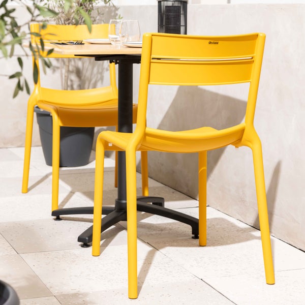 Moderne gelbe Gartenstühle aus Kunststoff an einem Bistro-Tisch auf einer hellen Terrasse. Oviala Logo.