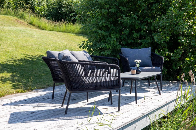 Gartenmöbel-Set mit Tisch und Sesseln auf einer Holzterrasse