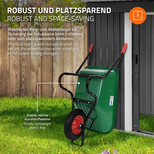 Grüne Schubkarre mit Kunststoffwanne und schwarzem Metallgestell, platzsparend senkrecht an einem Gartenhaus abgestellt.