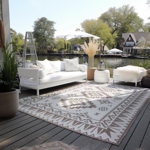 Terrasse mit Outdoor-Teppich, Sofa, Hocker und dekorativen Elementen