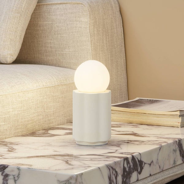 Tischleuchte mit kugelförmigem Lampenschirm auf einem Tisch neben einem Sofa