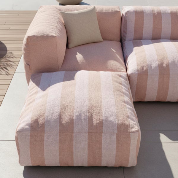Modulare Outdoor-Lounge in Rosa und Beige mit gestreiften Polstern aus strukturiertem Stoff auf einer Terrasse mit Holzdielen.
