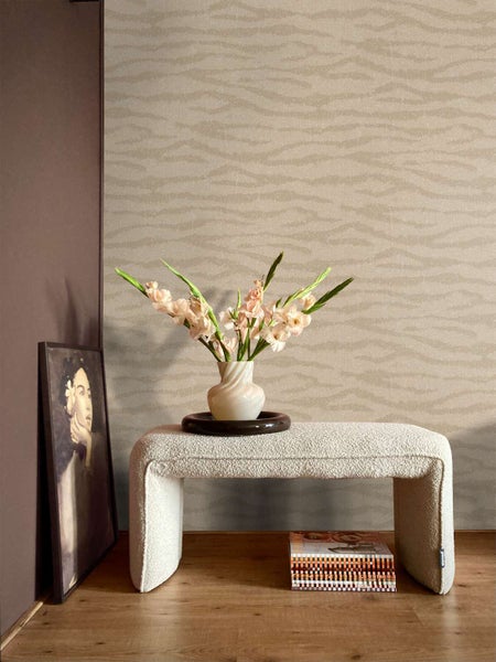 Wohnzimmer mit Vliestapete mit wellenförmigem Strukturmuster, Boucle Bank und Vase mit Blumen auf Holzboden.