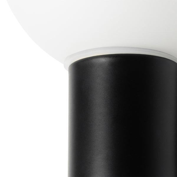 Detailaufnahme einer Leuchte mit schwarzem Fuß und weißem Lampenschirm