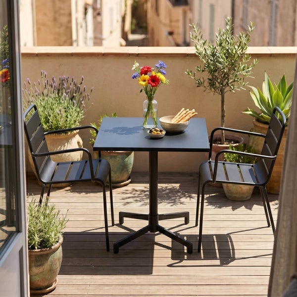 Gartenmöbel-Set bestehend aus einem quadratischen Bistrotisch und zwei Stühlen mit Armlehnen aus schwarzem Metall auf einer hellen Holzterrasse.