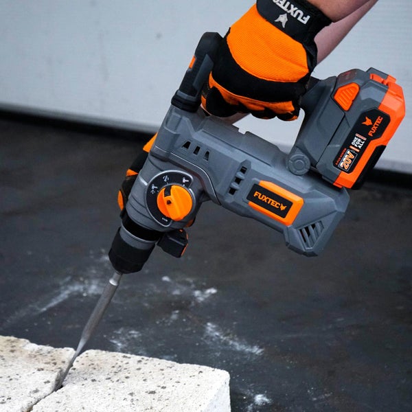 Ein akkubetriebener Fuxtec Bohrhammer mit 20 Volt Akku bei der Arbeit an einem Steinblock.