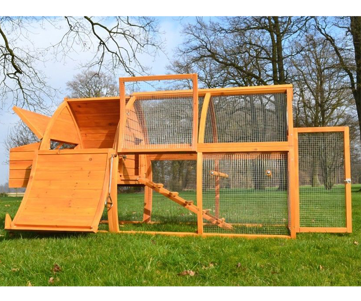Großer Hühnerstall aus hellem Holz mit integriertem Freilaufgehege, Drahtgeflecht, Rampe und geöffneten Türen auf einer Wiese.