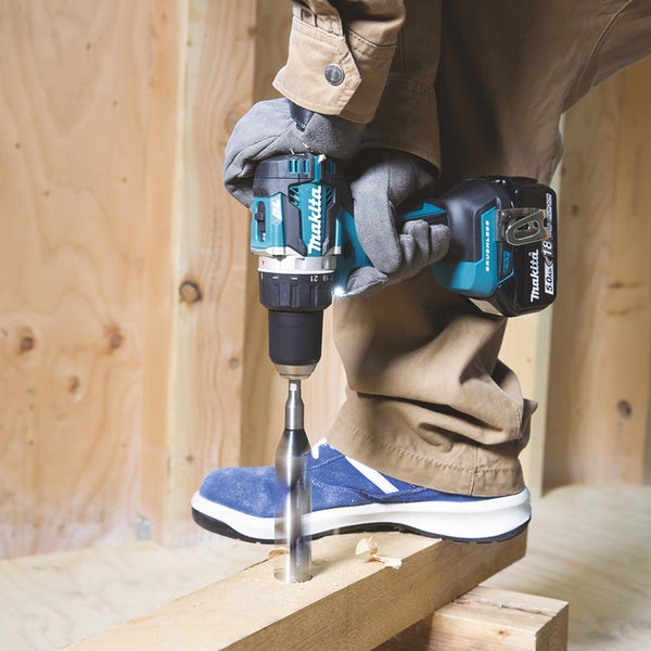 Eine Person bohrt mit einer Makita Bohrmaschine ein Loch in ein Holzbrett.