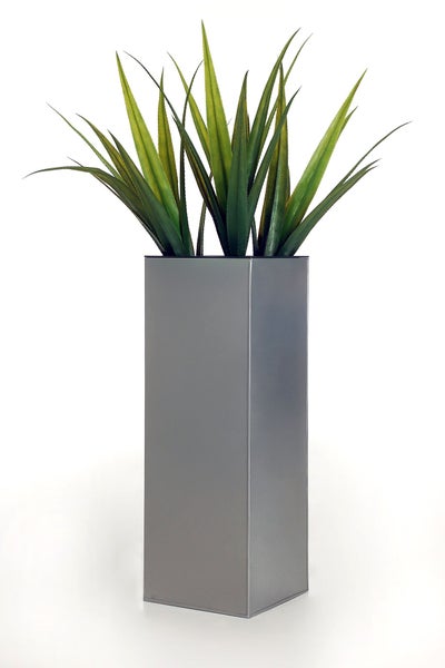 Hoher quadratischer Pflanzkübel in Silberoptik mit grüner Kunstpflanze mit langen spitzen Blättern.