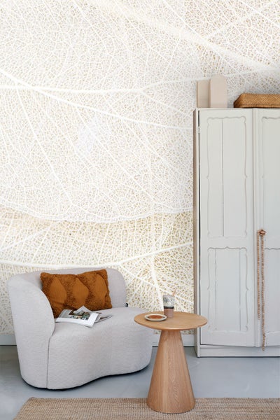 Wohnraum mit Blättertapete, Sessel und Holztisch für ein helles Ambiente.