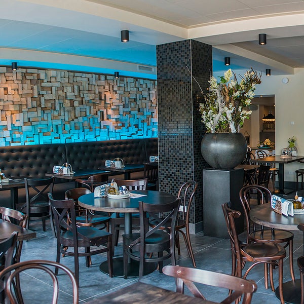 Innenraumansicht eines Restaurants mit Tischen, Stühlen und dekorativer Wandgestaltung