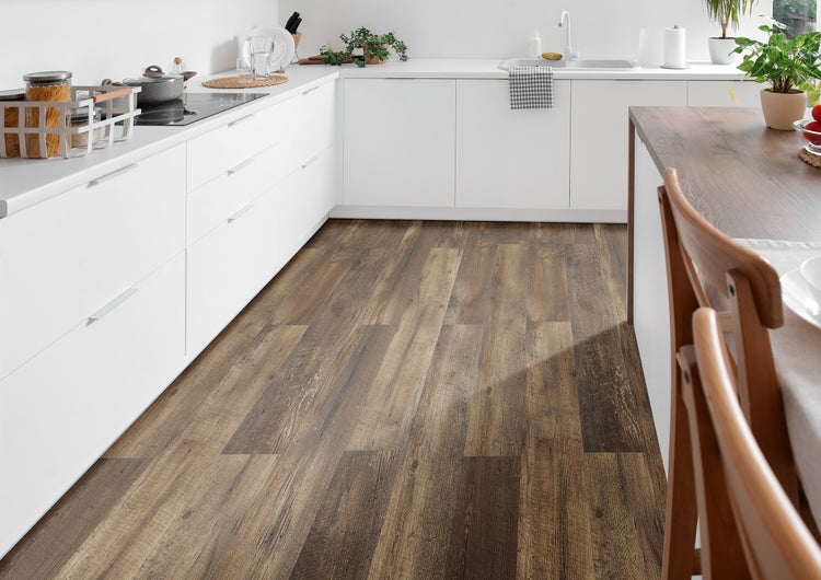 Helle, moderne Küche mit weißen grifflosen Schränken und dunklem Bodenbelag in rustikaler Holzoptik.