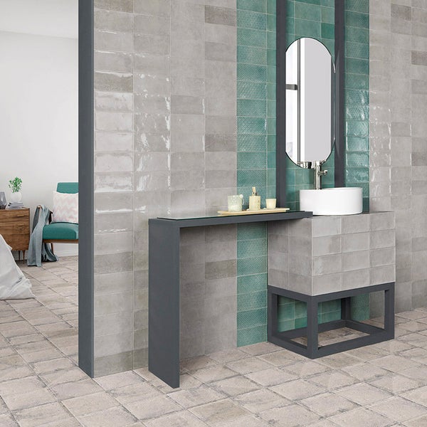 Modernes Badezimmer mit Wandfliesen in rechteckiger Optik, unterteilt in graue und grüne Akzentbereiche, mit einem Waschtisch und Rundspiegel.