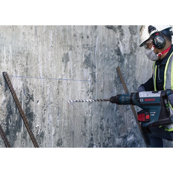 Ein Arbeiter bohrt mit einem Bohrhammer in eine Betonwand.