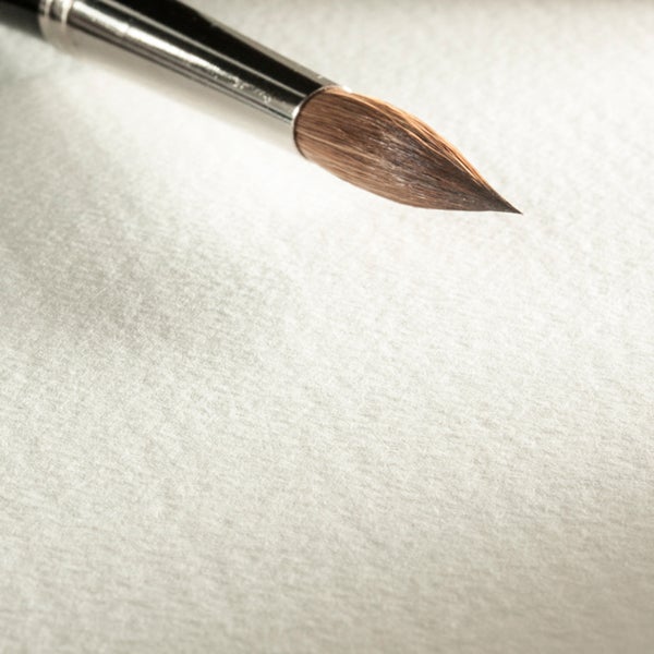 Spitzer Rundpinsel für Künstler mit Metallzwinge auf strukturiertem Papier.