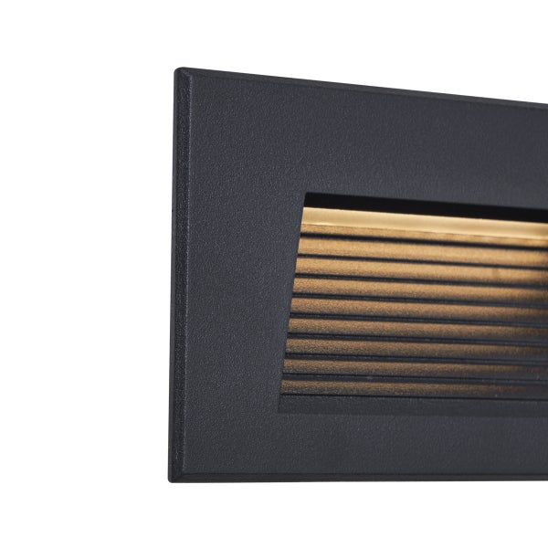 Schwarze, rechteckige LED Wandeinbauleuchte mit horizontalen Lamellen und warmweißem Licht.