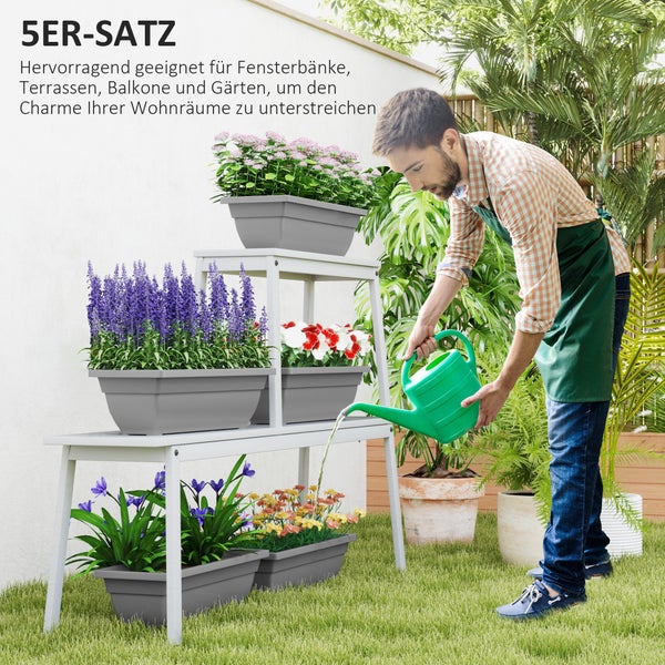 Mann gießt Blumen in einem 5-teiligen Set aus grauen Blumenkästen auf einem weißen Pflanzenregal im Garten.