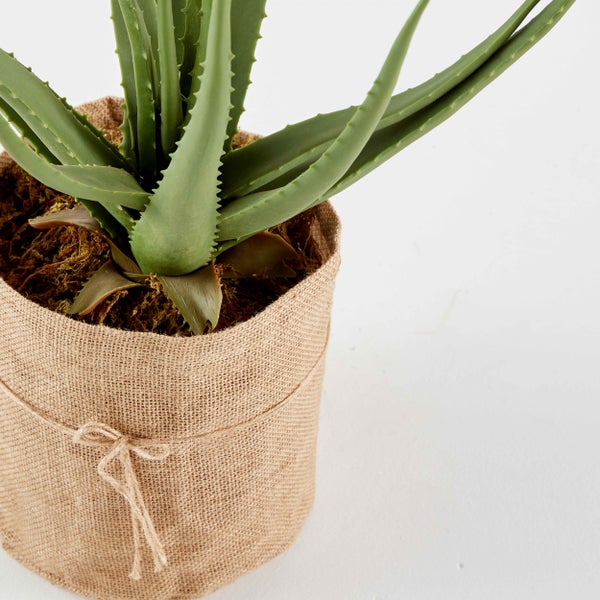 Künstliche Aloe Vera Pflanze im Topf mit Jutegewebe und dekorativer Kordel.