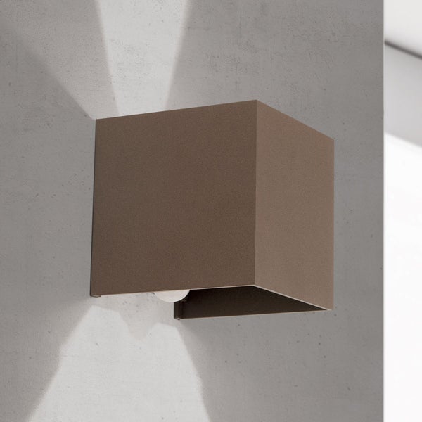 Würfelförmige Wandleuchte aus braunem Metall mit Up-and-Down-Lichteffekt an einer Wand montiert.