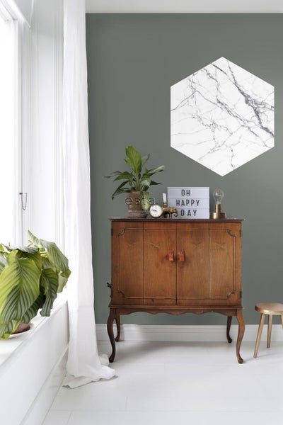 Wohnzimmerszene mit Holzkommode, Pflanzen und hexagonaler Wanddekoration