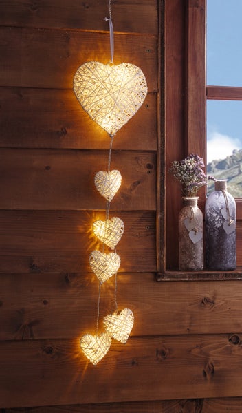 Dekorative Herz Lichterkette vor rustikalem Holzfenster