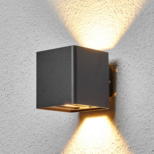 Würfelförmige LED-Außenwandleuchte in Anthrazit mit Lichtaustritt nach oben und unten an einer Wand montiert.