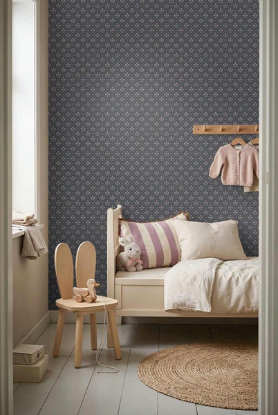 Dunkelblaue Mustertapete mit kleinen floralen Motiven in einem gemütlich eingerichteten Kinderzimmer mit Holzmöbeln und Rundteppich.