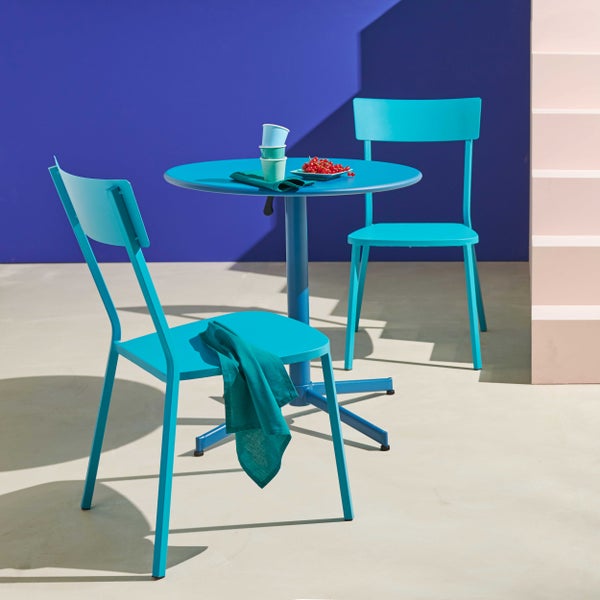 Modernes Gartenmöbel-Set aus türkisfarbenem Metall mit rundem Bistrotisch und zwei Stühlen in einer hellen, minimalistischen Umgebung.