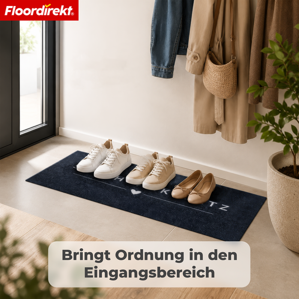 Floordirekt Logo. Ein dunkler Sauberlaufläufer im hellen Eingangsbereich mit ordentlich aufgereihten Schuhen, einer Garderobe und einer Pflanze.
