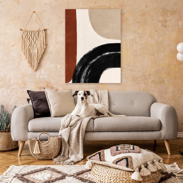 Ein gemütliches Wohnzimmer mit einem hellen Sofa, auf dem ein Hund liegt, dekoriert mit abstrakter Wandkunst, Makramee und Naturmaterialien.