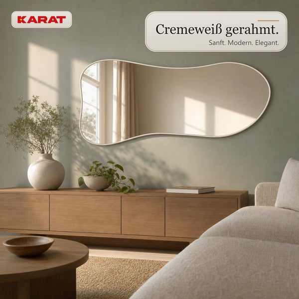 Wandspiegel mit organisch geformtem Rahmen in einem Wohnzimmer mit Holzkommode und Zimmerpflanzen.