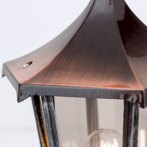 Nahaufnahme einer Außenleuchte in Laternenform mit gebürstetem Metalldach und Glaseinsätzen.