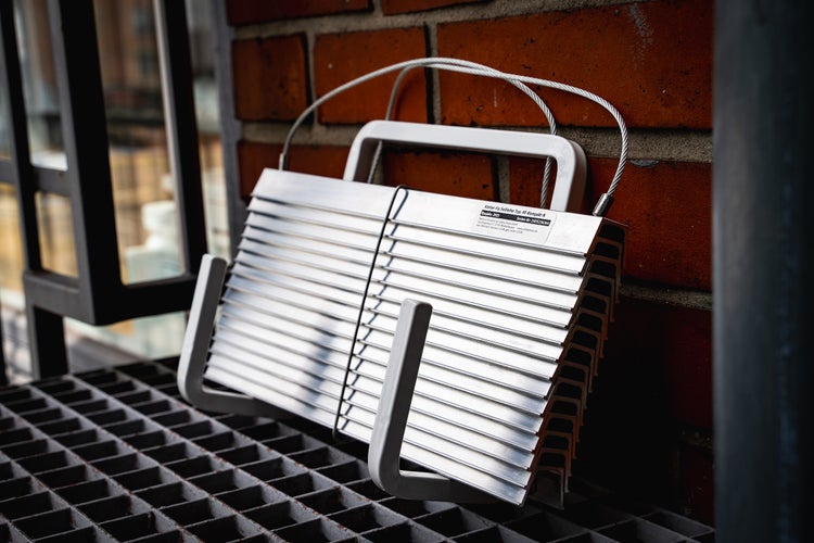 Kletter-Fix Seilleiter Kompakt-N auf einem Gitterrost vor einer Ziegelwand