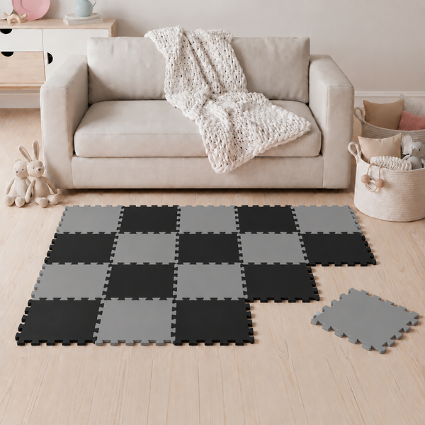 Puzzlematte aus Schaumstoff in Schachbrettoptik als Bodenbelag für Kinderzimmer vor einem Sofa.