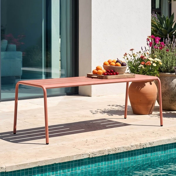 Moderne Gartenbank aus Metall mit Lamellenoberfläche auf einer hellen Terrasse am Pool, dekoriert mit einer Obstschale.