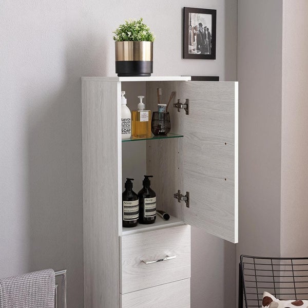 Hoher Badezimmerschrank in heller Holzoptik mit einer geöffneten Tür, einem Glaseinlegeboden für Pflegeprodukte und einer Schublade.
