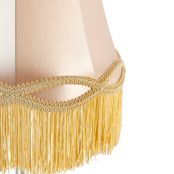 Detailaufnahme eines Lampenschirms aus Stoff mit dekorativer Borte und Fransen.