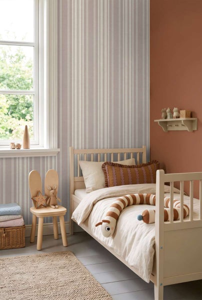Gemütliches Kinderzimmer mit gestreifter Tapete, Einzelbett aus Holz, Stuhl mit Hasenmotiv, Wandregal und Naturtextilien in warmen Erdtönen.
