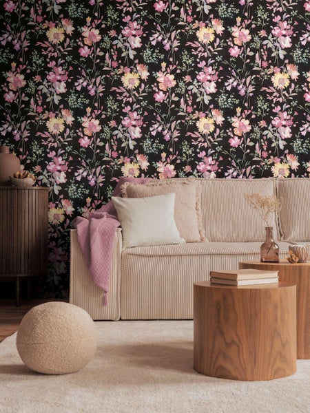 Wohnzimmer mit Vliestapete mit Blumenmuster vor einem Sofa mit Kissen und Holztischen in einer eleganten und gemütlichen Wohnraumgestaltung