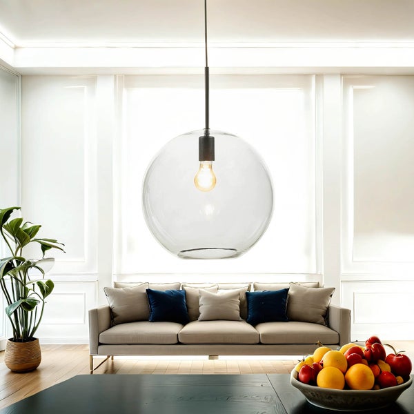 Wohnzimmer mit Sofa, Zimmerpflanze und runder Pendelleuchte aus Glas