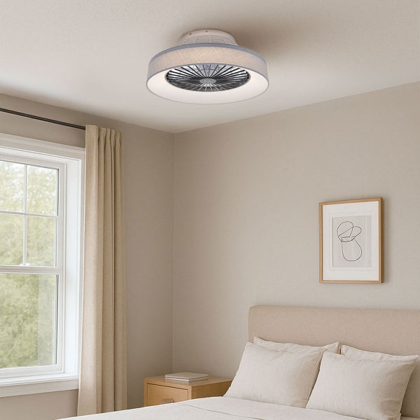 Moderner Deckenventilator mit Textilschirm und integrierter Leuchte in einem hellen Schlafzimmer mit Bett, Vorhängen und Kunstwerk an der Wand.