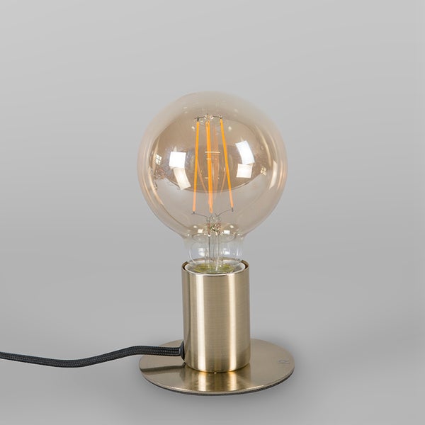 Minimalistische Tischleuchte mit zylindrischem Metallsockel in Messing-Optik und großer Filament-Globelampe mit bernsteinfarbenem Glas.