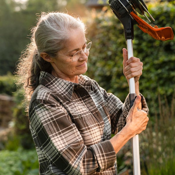 Frau bedient einen Obstpflücker im Garten.